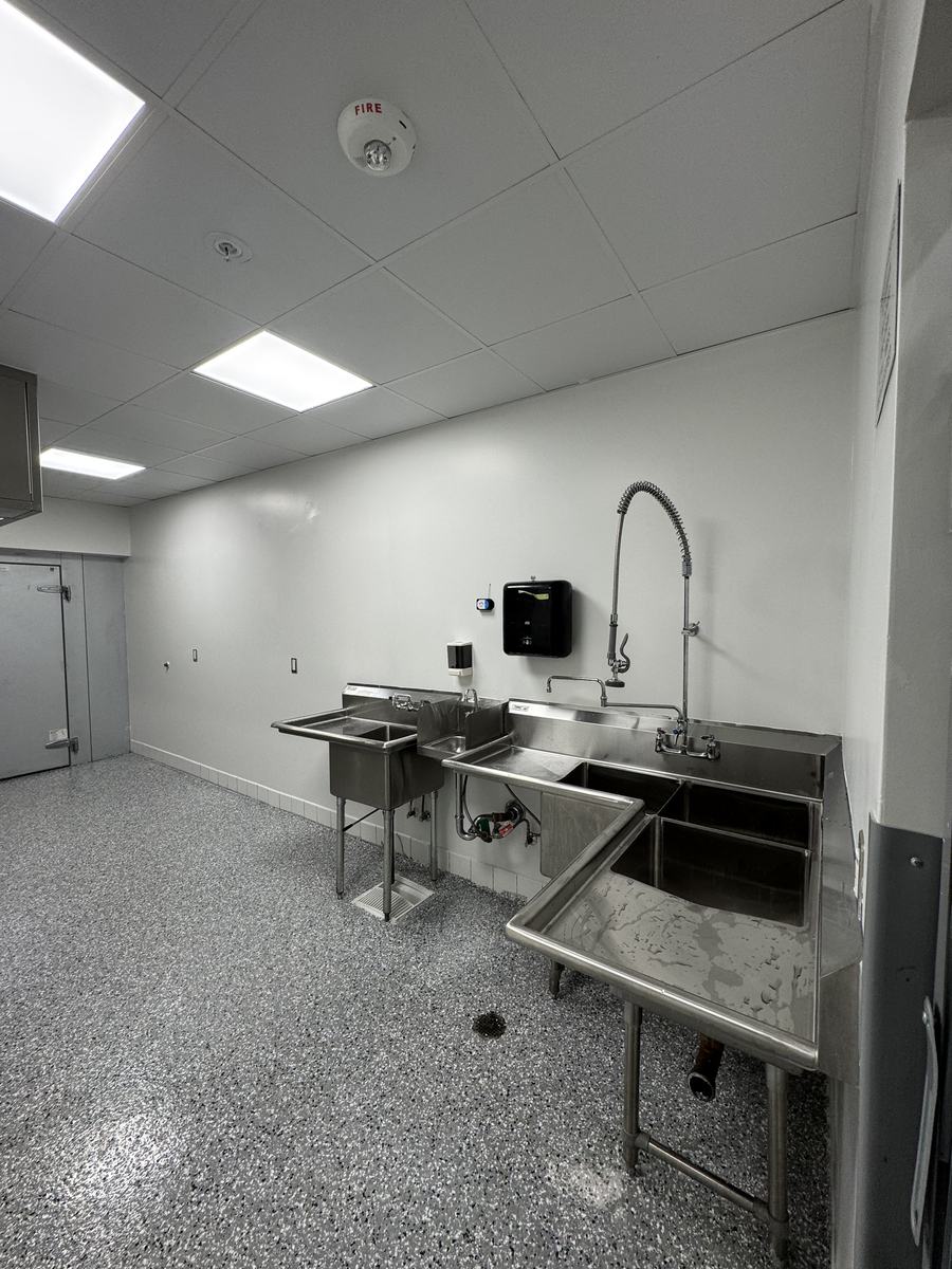 Completed commercial kitchen with stainless steel sinks, wash station and epoxy flooring