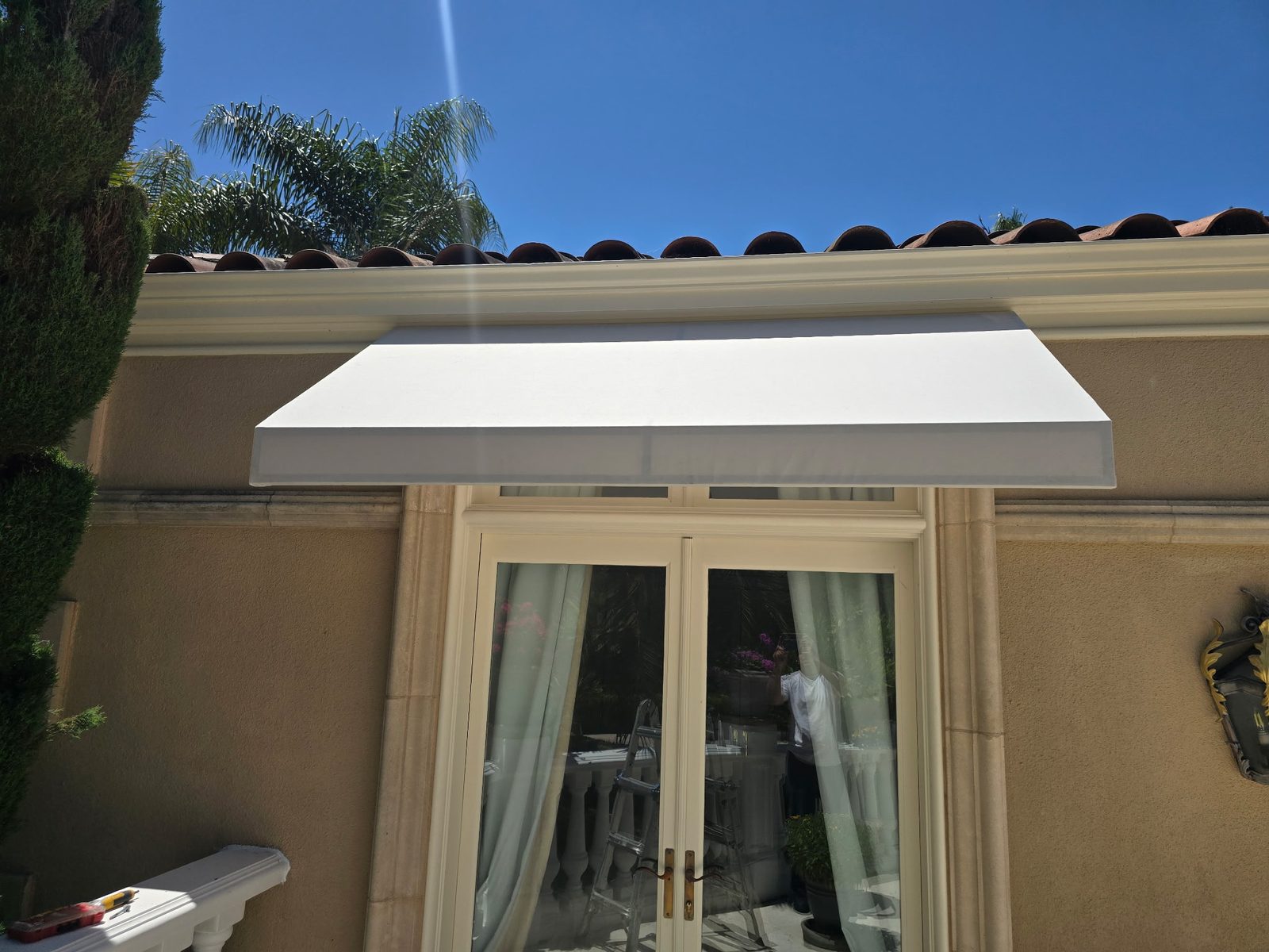 Close view of a restored white awning fitted above a set of French doors