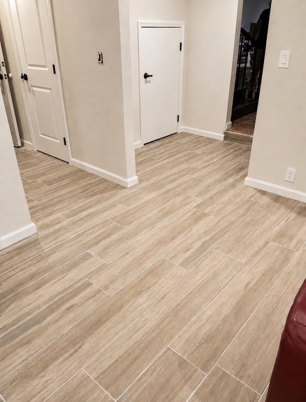Wood-look plank tile flooring running through a hallway past white panel doors